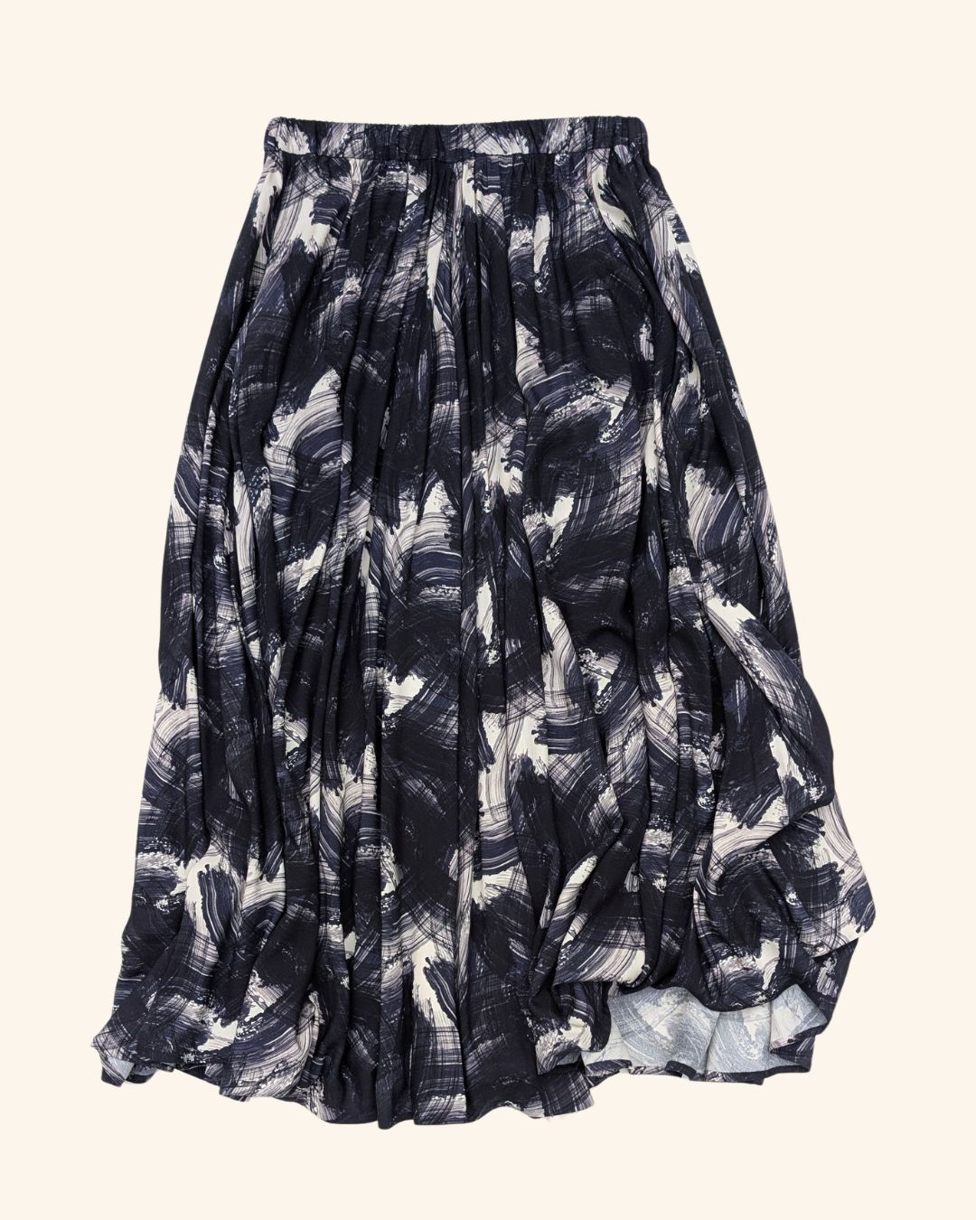 A pleated midi skirt with an abstract brushstroke pattern in navy blue, black. and white, shown against a plain white background.